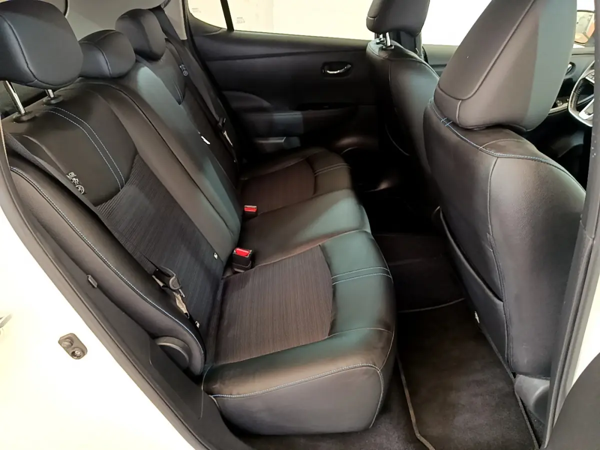 Vue intérieure côté gauche des sièges arrière noirs avec surpiqûres bleues d'une Nissan Leaf 62 kWh Business+ blanche de 2020.