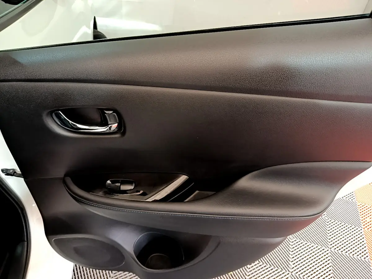 Porte intérieure côté gauche noire de Nissan Leaf blanche 2020, avec poignée chromée et commande de vitre.