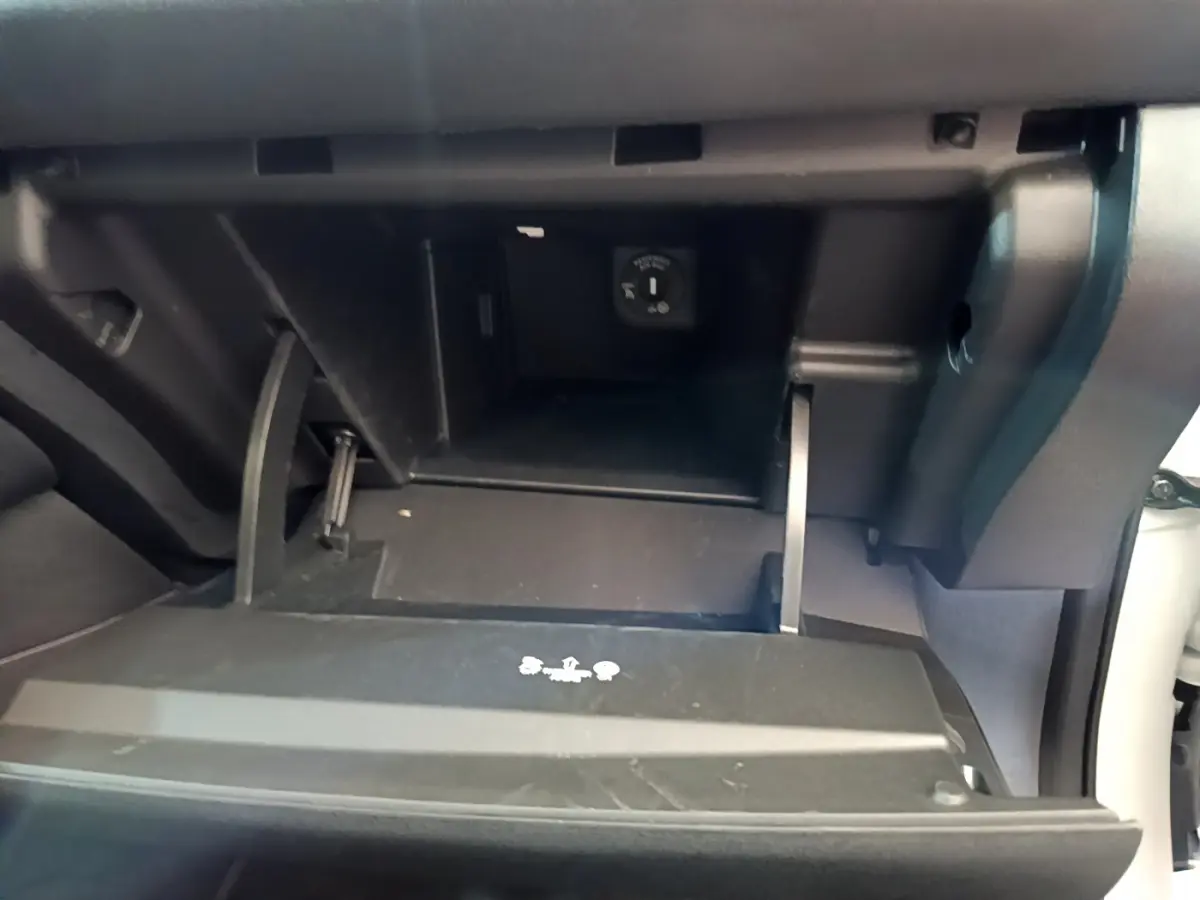 Vue rapprochée de la boîte à gants ouverte du Nissan Leaf blanc 62 kWh 217ch Business+ avec prise 12V visible.