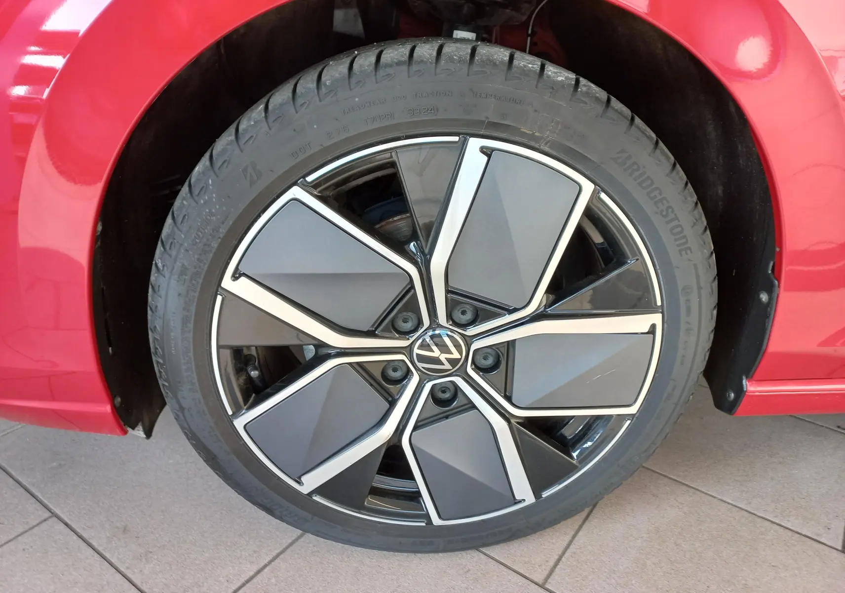 Gros plan sur la jante alliage 18'' Leeds et pneu Bridgestone du côté gauche d'une Volkswagen Golf Rouge Roi 2024.