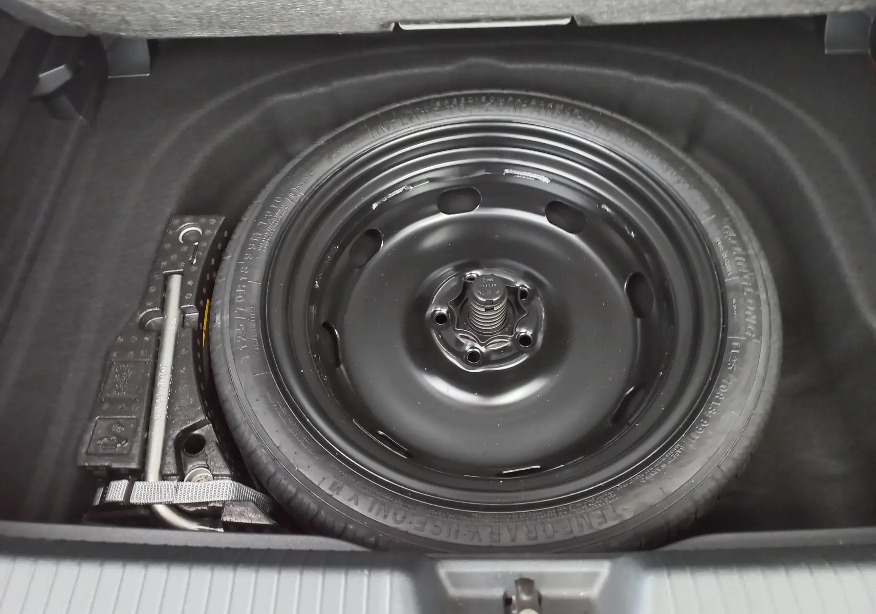 Roue de secours noire et cric dans le coffre d'une Volkswagen Golf 2.0 TDI 150 DSG7 Style 2024 Rouge Roi