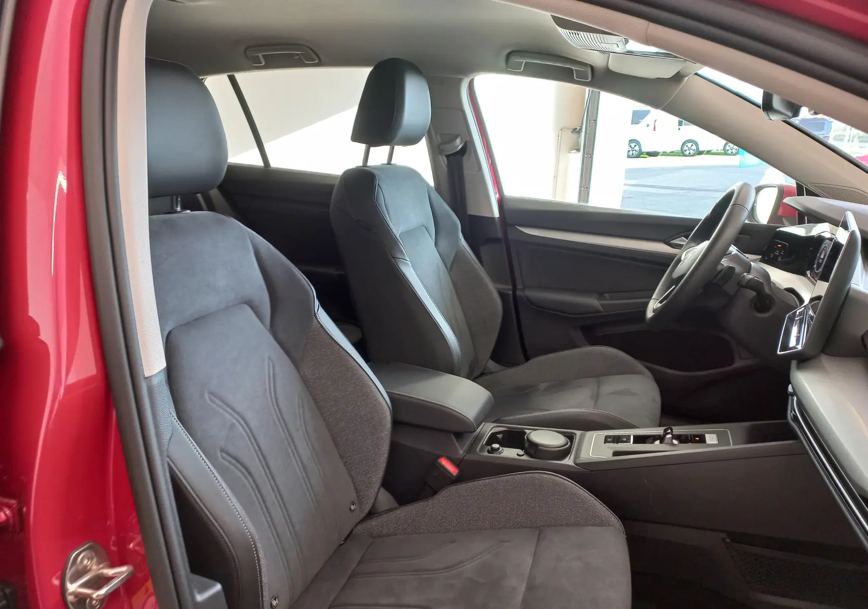 Intérieur avant droit d'une Volkswagen Golf 2.0 TDI rouge Roi, sièges chauffants et volant cuir multifonction visible.