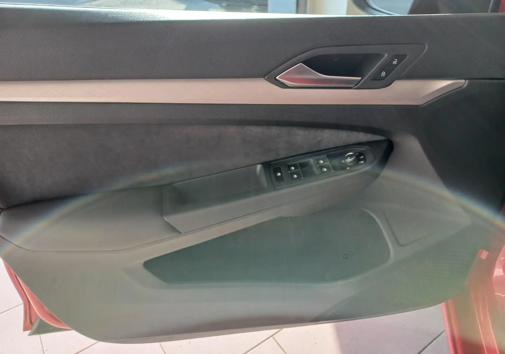 Vue intérieure de la porte avant gauche d'une Volkswagen Golf Rouge Roi, avec commandes de vitres et verrouillage.