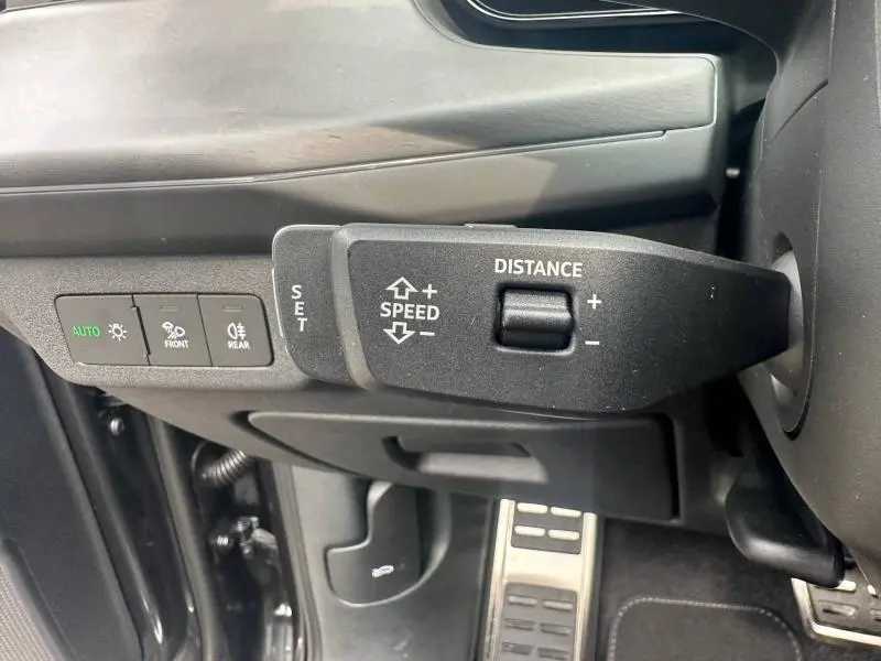 Gros plan sur la commande de régulateur de vitesse et les boutons d’éclairage à gauche du volant d’un Audi Q3 gris 2026.
