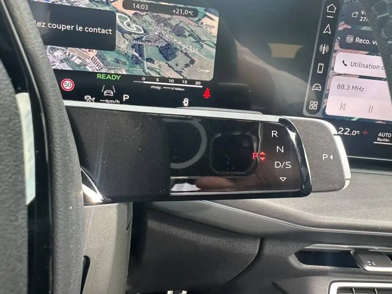 Vue rapprochée du levier de vitesses automatique noir et brillant de l'Audi Q3 gris 2026 avec affichage digital et tableau de bord numérique.