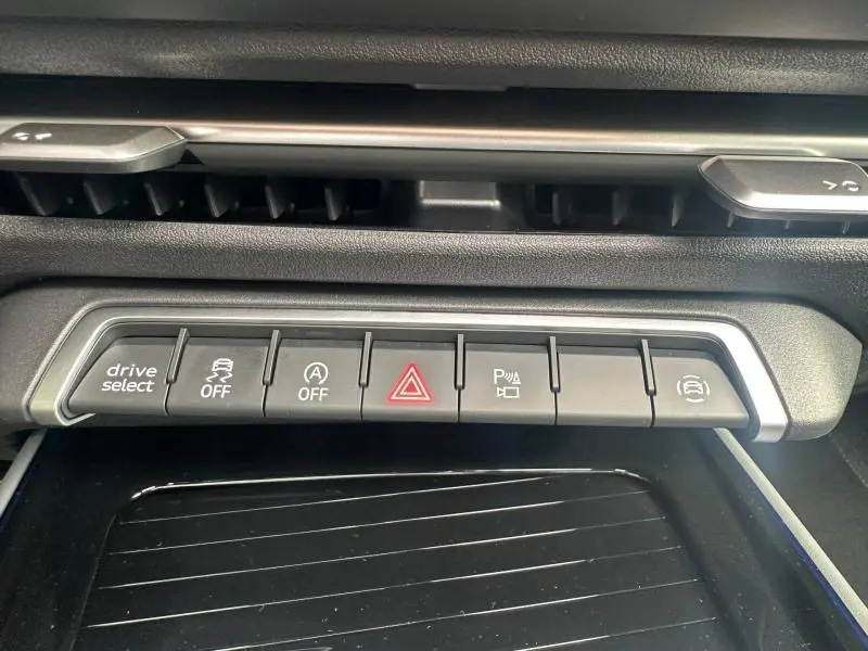 Boutons de commande du tableau de bord de l'Audi Q3 gris 2026, vue rapprochée centrée sur les fonctions d'aide à la conduite.