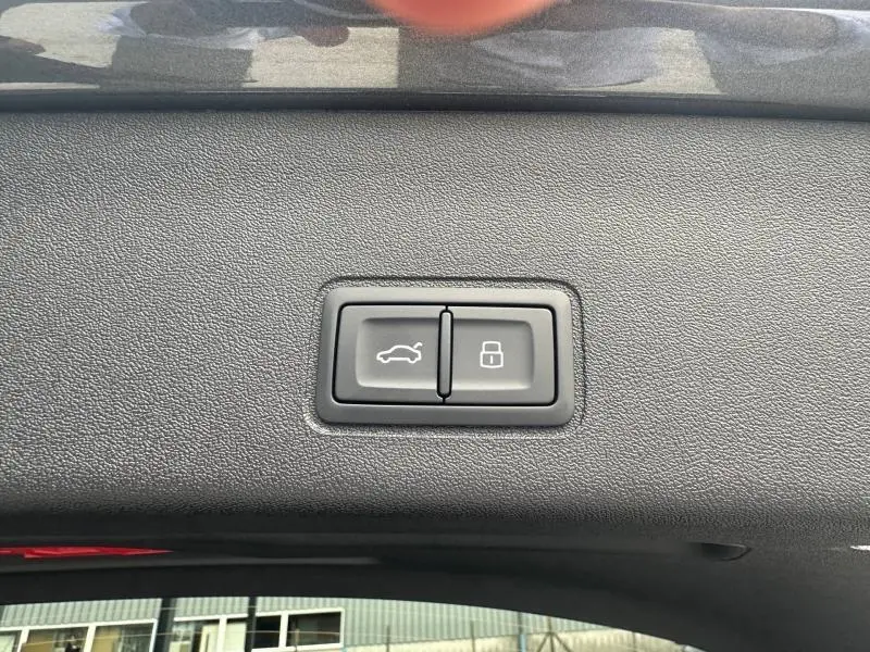 Boutons de commande du hayon et de verrouillage intégrés dans le panneau intérieur gris du coffre d’un Audi Q3 2026.