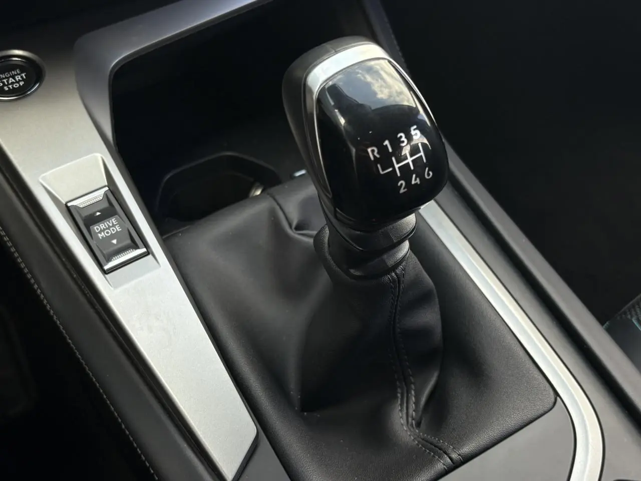 Gros plan sur levier de vitesses manuel noir et bouton Drive Mode dans l’habitacle d’une Peugeot 308 2024.