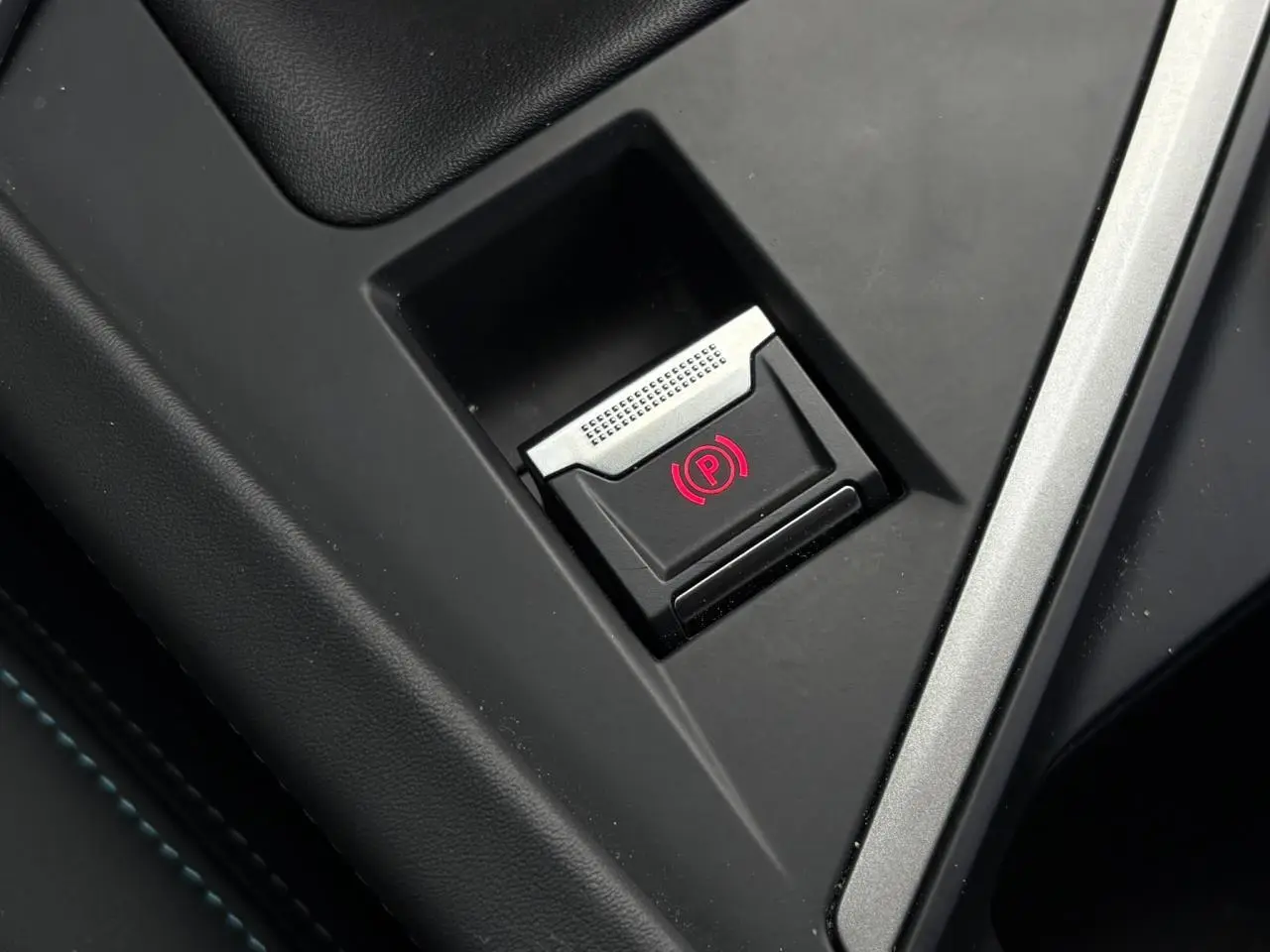 Gros plan sur le frein de parking électrique avec témoin rouge dans l'habitacle noir du Peugeot 308 2024.
