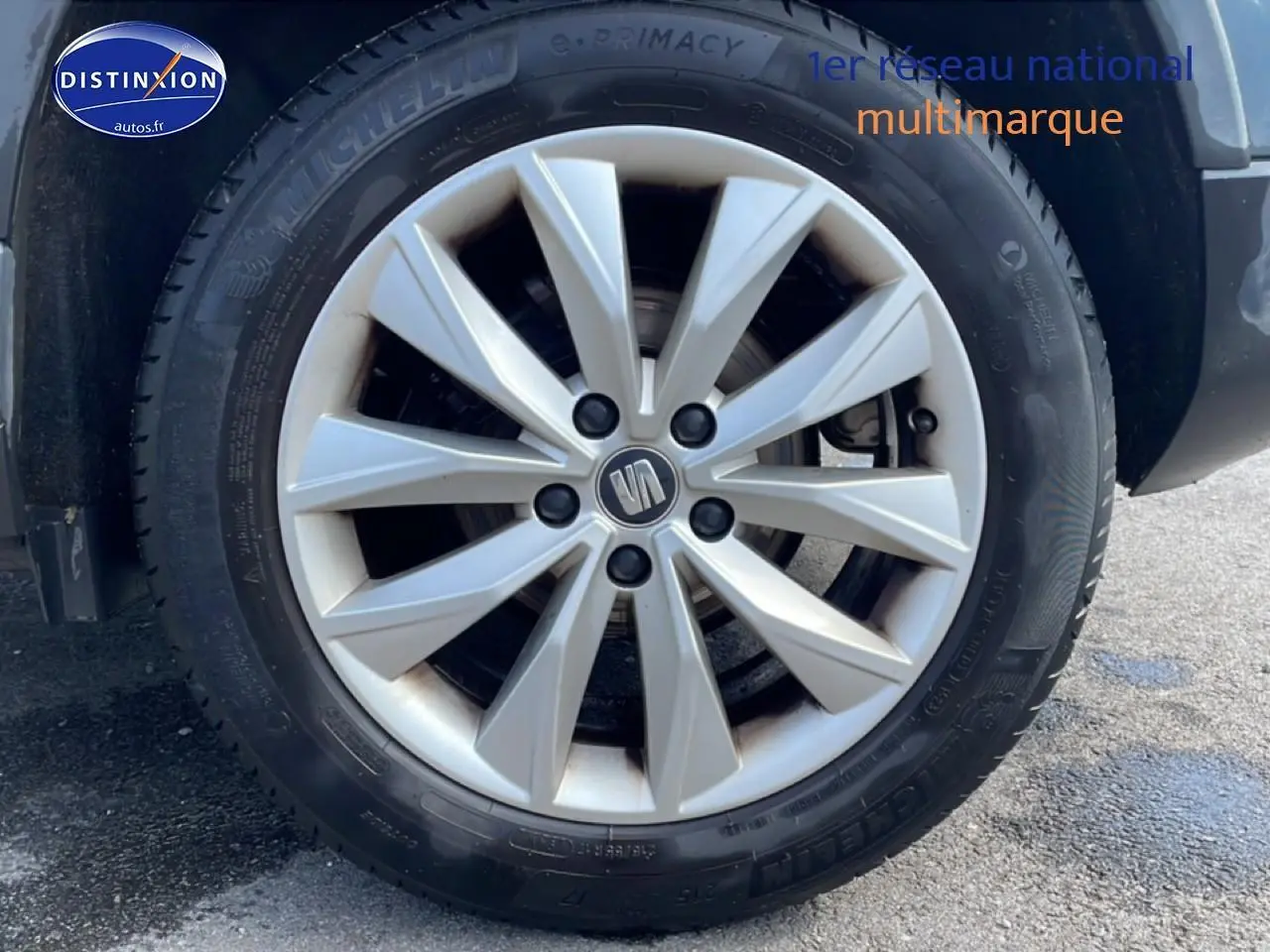 Gros plan sur la roue avant droite du SEAT Ateca bleu/gris avec jante alliage et logo central visible.