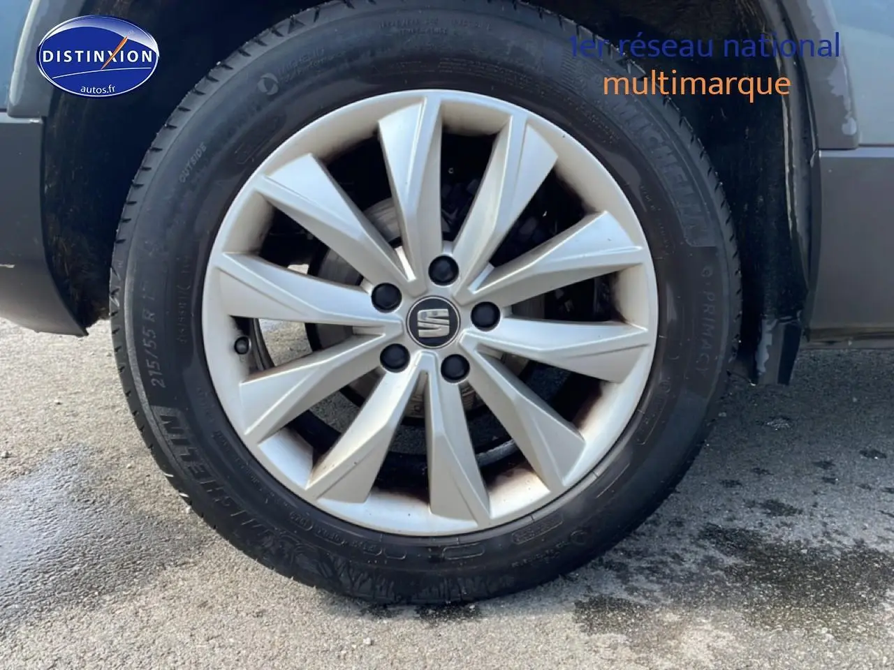 Gros plan sur la roue avant gauche du SEAT Ateca bleu/gris avec jante alliage et logo central Seat visible.