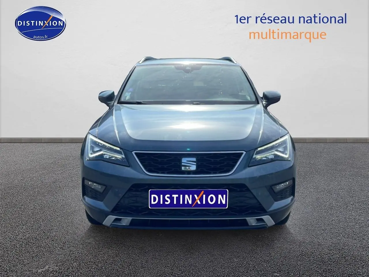 Vue frontale d'un SEAT Ateca bleu/gris 2019 avec calandre noire et phares LED allumés sur fond neutre.