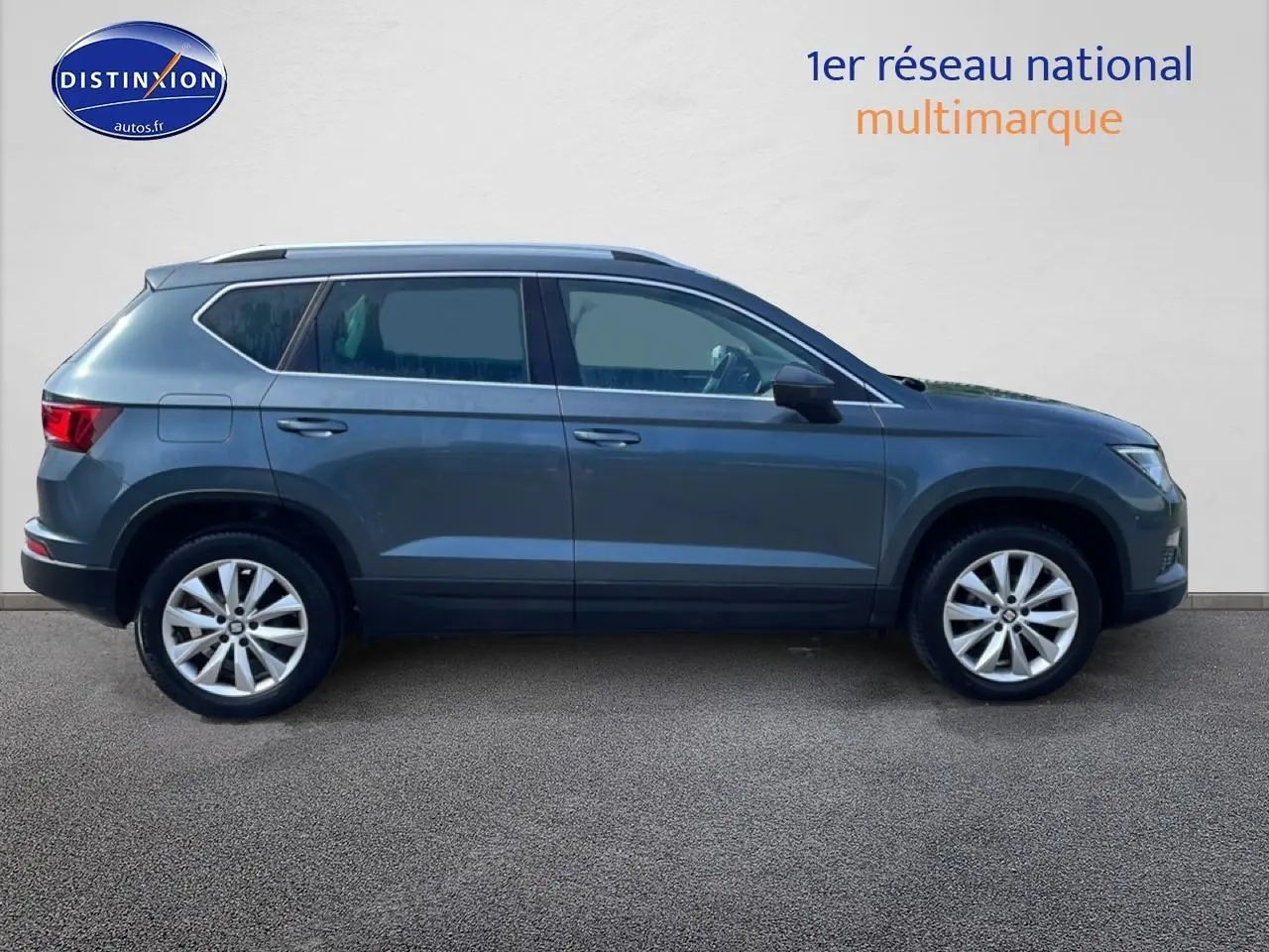 Vue latérale droite d'un SEAT Ateca 2019 bleu/gris avec jantes alu et barres de toit, sur fond neutre.