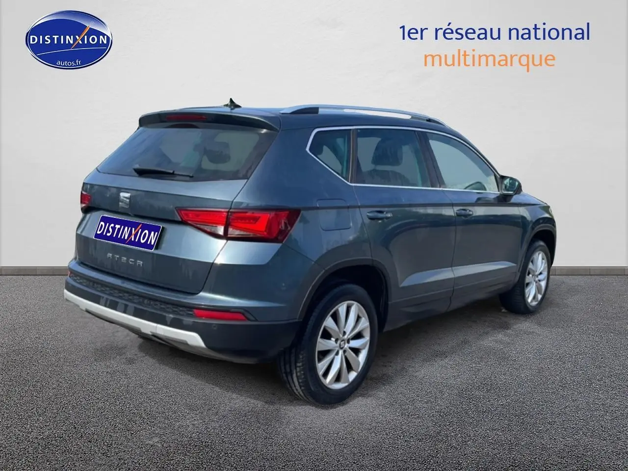 Vue 3/4 arrière droite d'un SEAT Ateca bleu/gris avec jantes alu et barres de toit visibles.