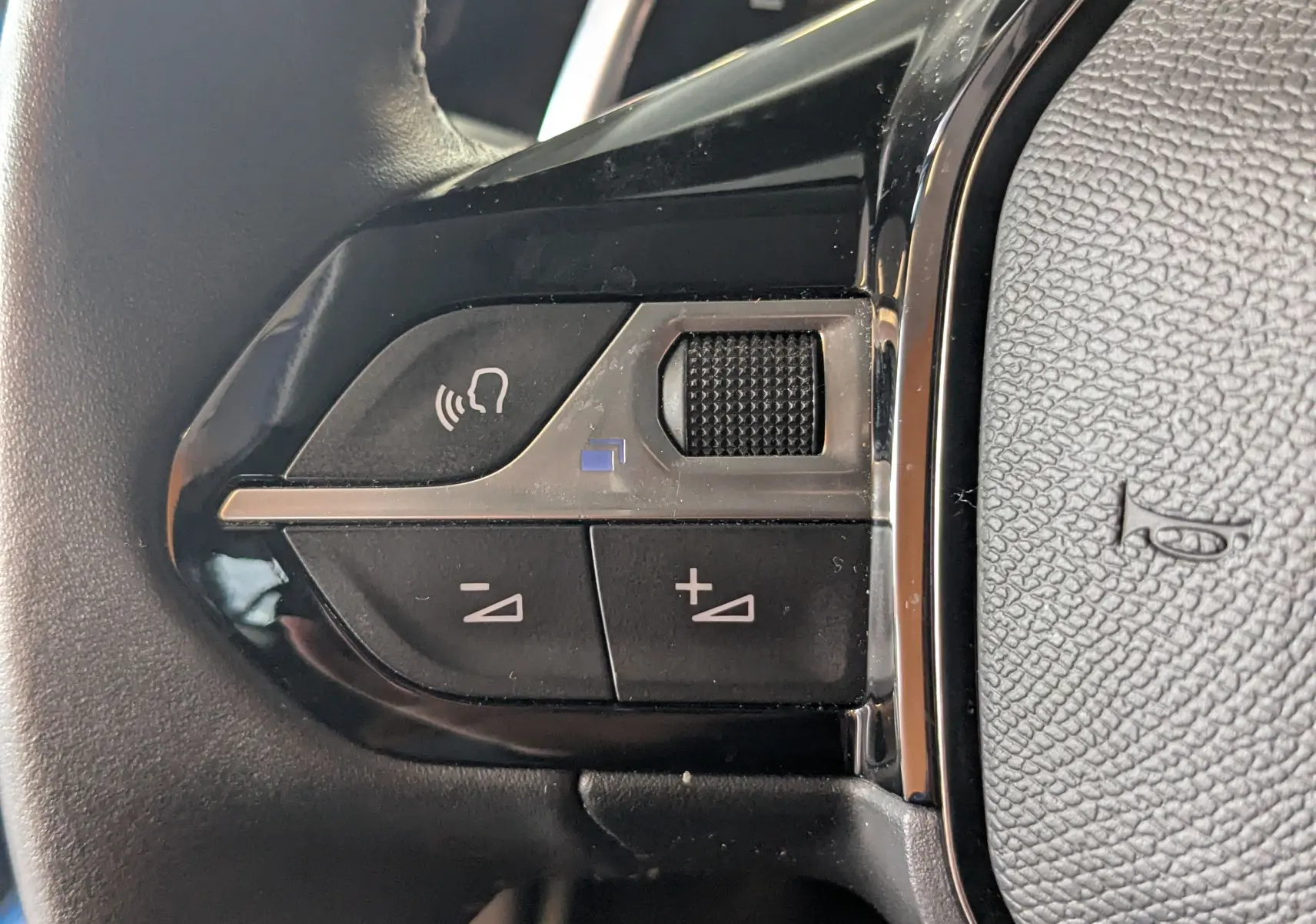 Gros plan sur les commandes noires du volant côté gauche du Peugeot 2008 1.5 BlueHDi 130 de 2022.