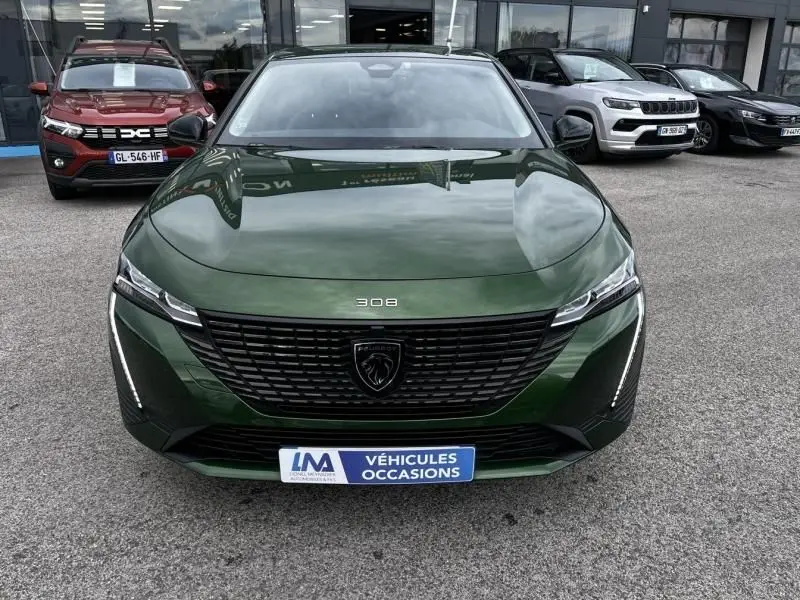 Vue de face d'une Peugeot 308 1.2 PureTech 130 Allure vert olivine 2023 avec calandre noire et logo lion central.
