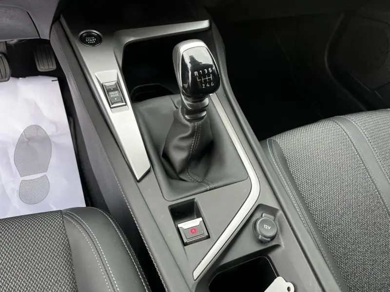 Vue rapprochée de la console centrale de la Peugeot 308 1.2 PureTech 130 Allure 2023 avec levier de vitesse manuel et bouton start/stop.
