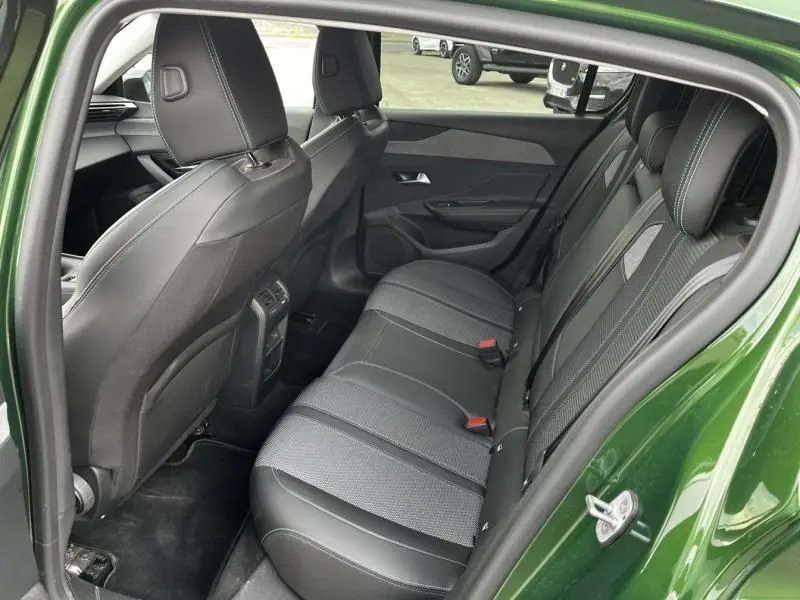 Vue intérieure arrière côté droit de la Peugeot 308 1.2 PureTech 130 Allure 2023 en vert olivine, montrant les sièges en tissu et cuir noir.