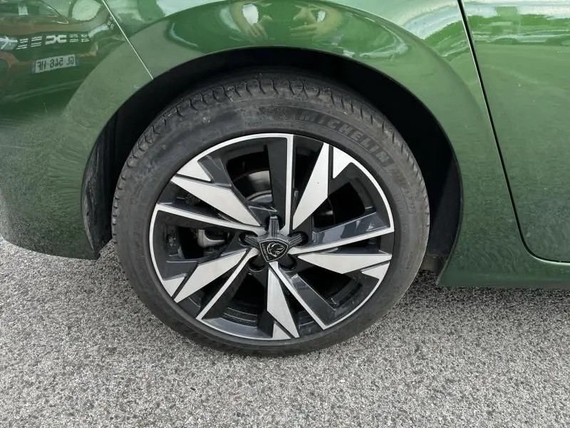 Gros plan sur la roue arrière droite d'une Peugeot 308 1.2 PureTech 130 Allure 2023 vert olivine avec jante alliage noire et argent.