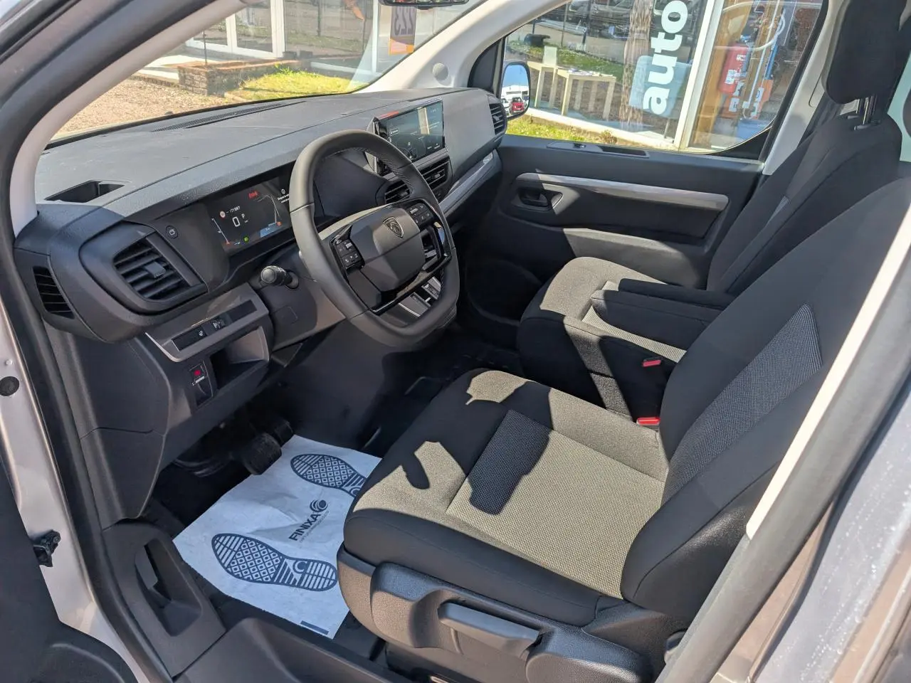 Vue intérieure côté conducteur du Peugeot Expert Fourgon XL 2026, montrant sièges tissu bi-ton gris et tableau de bord numérique.