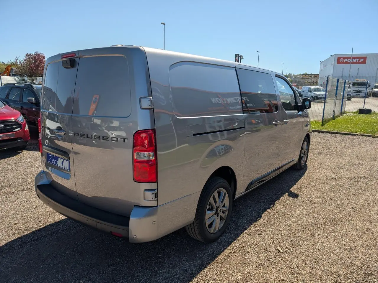 Vue 3/4 arrière droit d'un Peugeot Expert Fourgon gris métallisé avec jantes alliage 17'' et portes arrière tôlées ouvertes.