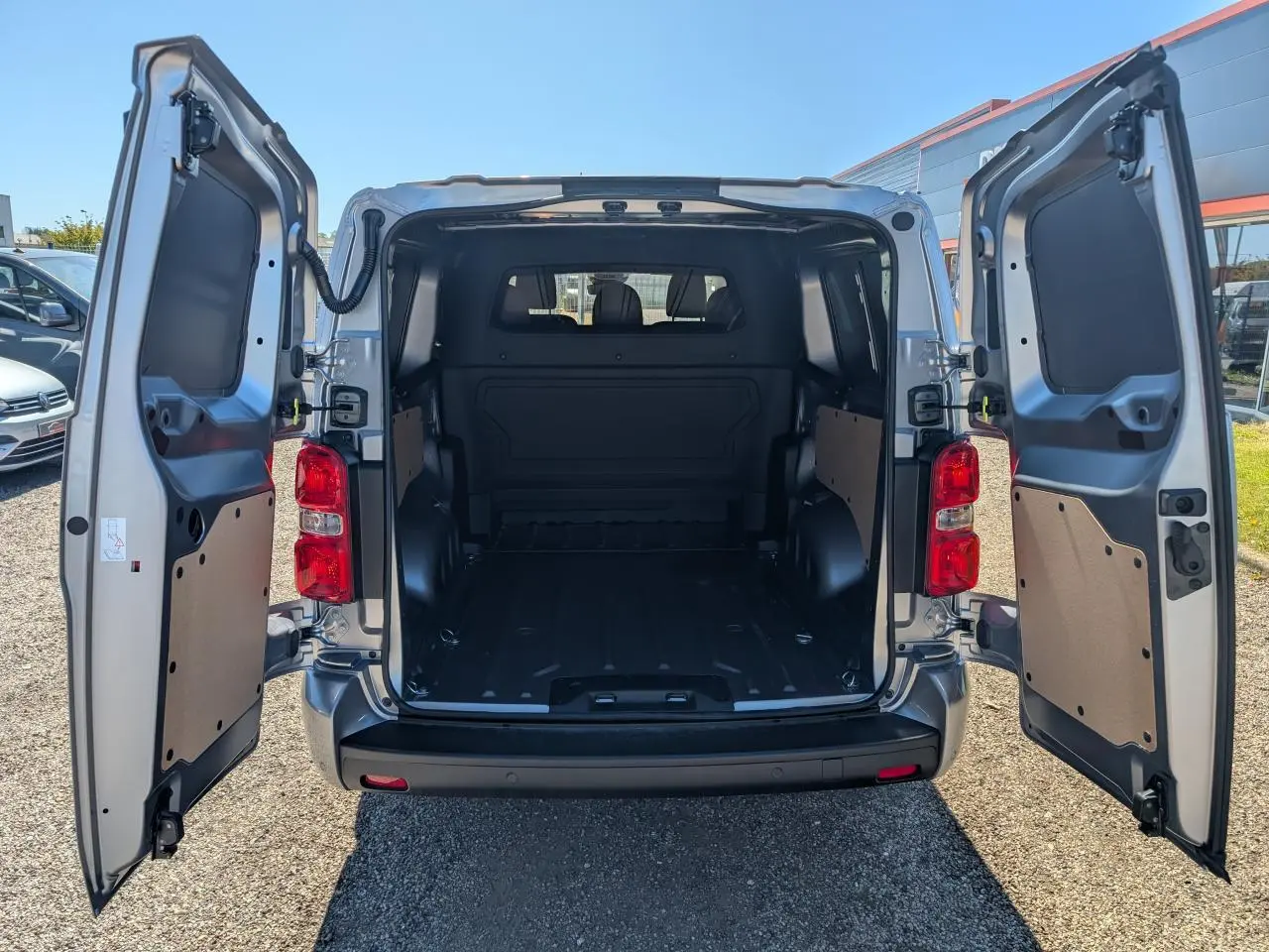 Vue arrière du Peugeot Expert Fourgon gris avec portes battantes ouvertes montrant l'espace de chargement vide.