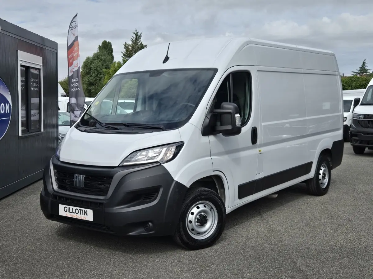 Fiat Ducato Fourgon blanc en 3/4 avant droit, avec pare-chocs noirs et calandre distinctive.