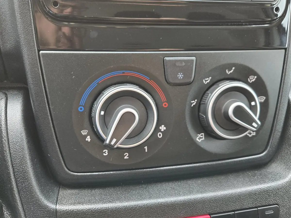 Gros plan sur les commandes de climatisation du Fiat Ducato Fourgon blanc, boutons de réglage température et ventilation.