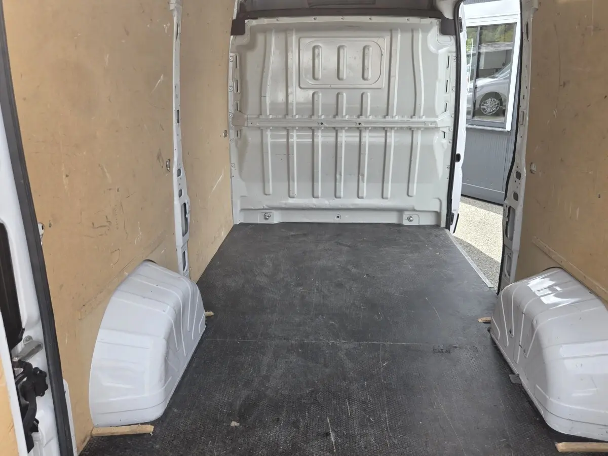 Intérieur du fourgon blanc Fiat Ducato MH2 3T 120ch, vue de l’espace de chargement avec cloison pleine et plancher noir.