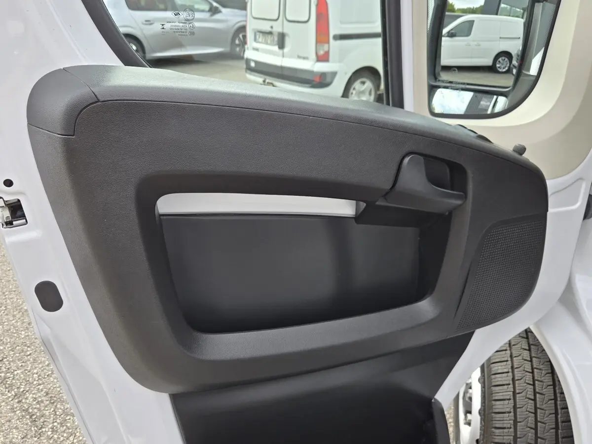 Vue rapprochée de la porte avant droite blanche du FIAT Ducato Fourgon 2023 avec panneau intérieur noir et poignée intégrée.