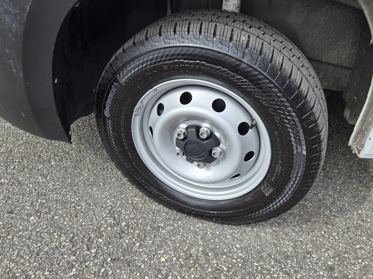 Gros plan sur la roue avant droite du FIAT Ducato Fourgon blanc, jante acier grise avec logo FIAT central.