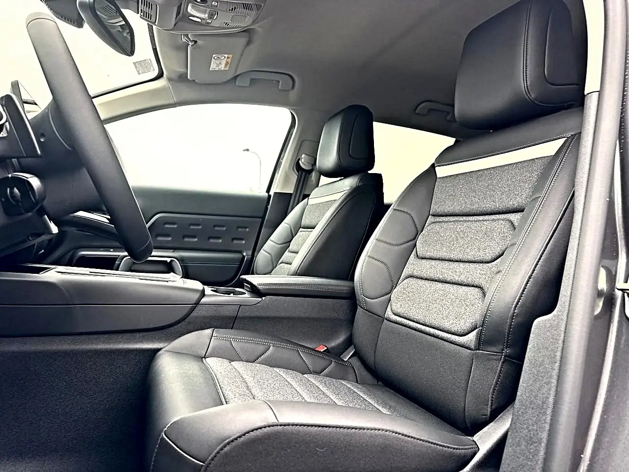Vue intérieure côté conducteur du Citroën C5 Aircross 2025, sièges en cuir et tissu gris avec accoudoir central.