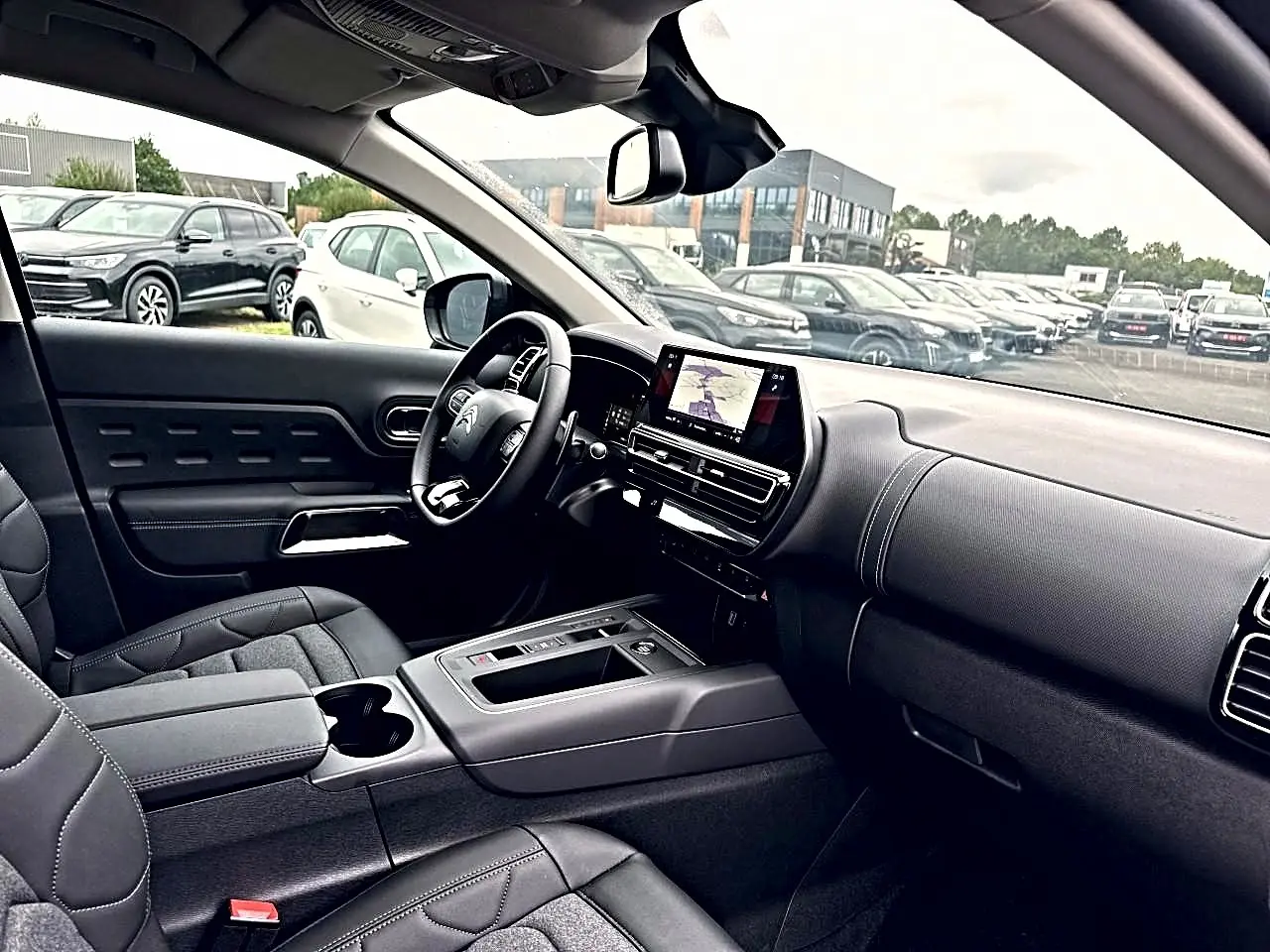 Vue intérieure côté conducteur du Citroën C5 Aircross 2025 avec tableau de bord noir et écran tactile central.