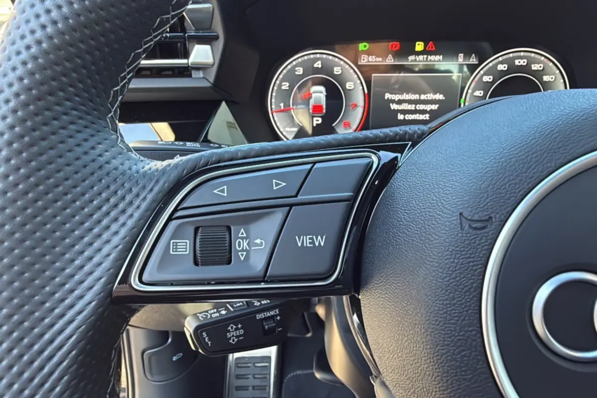 Gros plan sur le volant cuir à méplat de l'Audi A3 2025 avec commandes multifonctions et tableau de bord numérique.