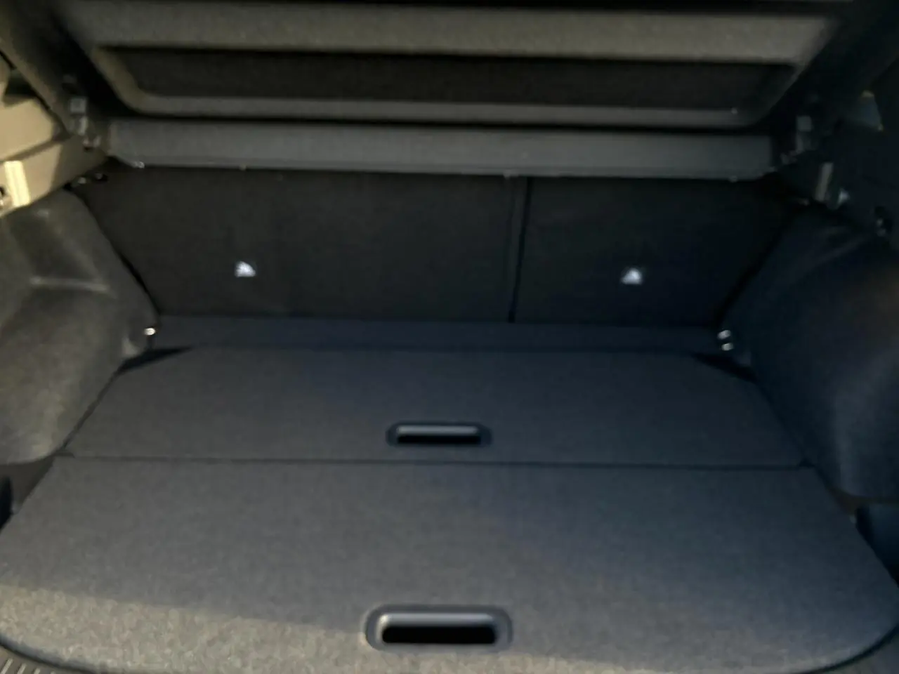 Coffre ouvert du Nissan Qashqai III noir, vue intérieure montrant le plancher de coffre modulable et les côtés tapissés.