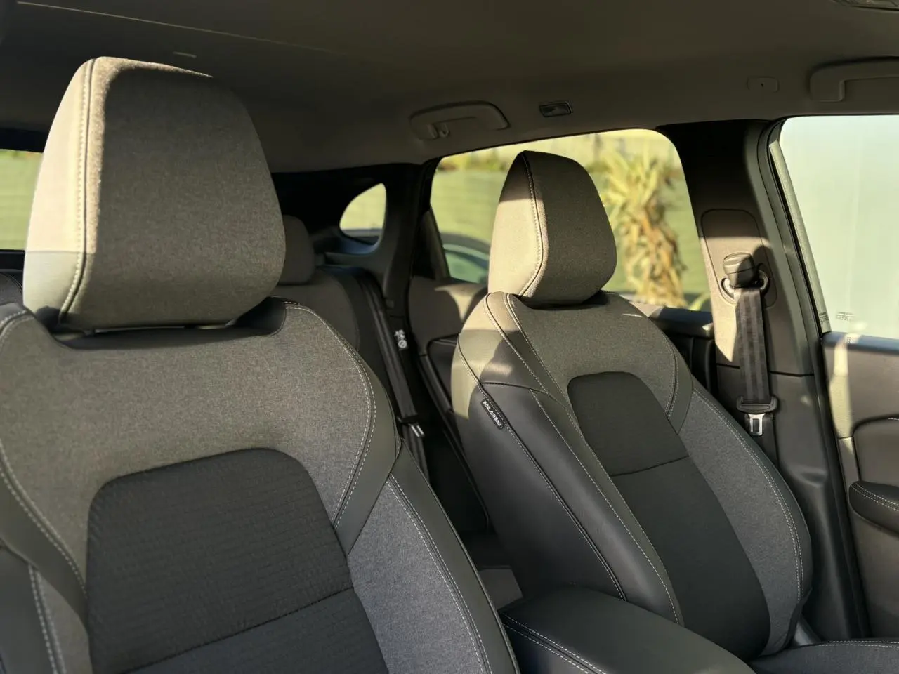 Vue intérieure montrant les sièges avant gris et noirs du Nissan Qashqai III 2025, avec détails en cuir et tissu.