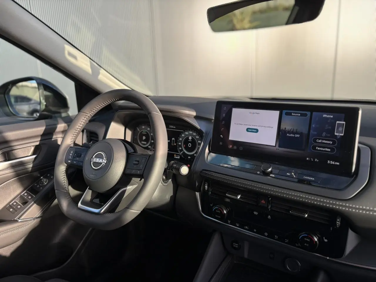 Vue intérieure côté conducteur du Nissan Qashqai 2025 noir, avec volant cuir et écran tactile large sur tableau de bord.