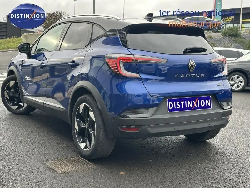 Renault Captur 1.6 E-Tech hybride 2025 en bleu Iron avec toit noir, vue 3/4 arrière droit, jantes noires distinctives.