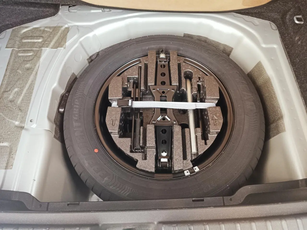 Vue plongeante sur la roue de secours et son kit d'outils dans le coffre d'une Skoda Kamiq 2025.