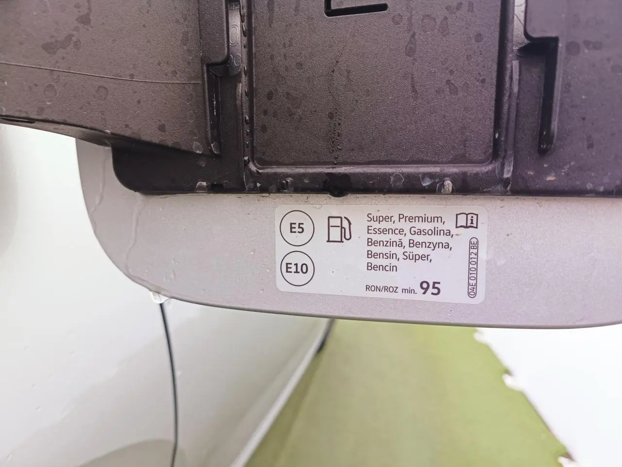 Vue rapprochée de l'intérieur de la trappe à carburant d'une Skoda Kamiq argent avec toit noir, étiquette essence E5 et E10 visible.