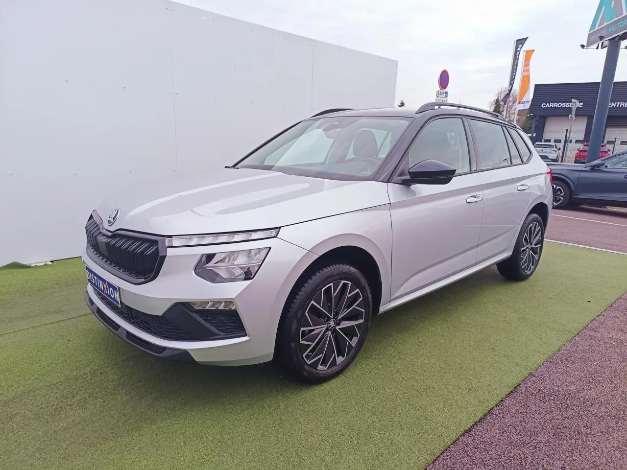 Vue 3/4 avant droite du Skoda Kamiq 2025 argent brillant avec toit noir et jantes alliage 17 pouces.