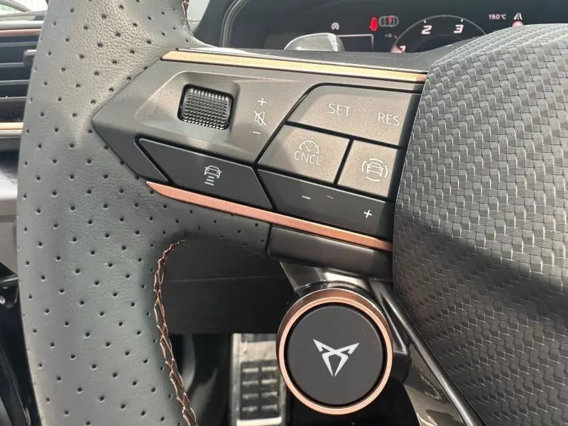 Gros plan sur la partie gauche du volant perforé noir du CUPRA Formentor 2026 avec commandes et logo cuivré.