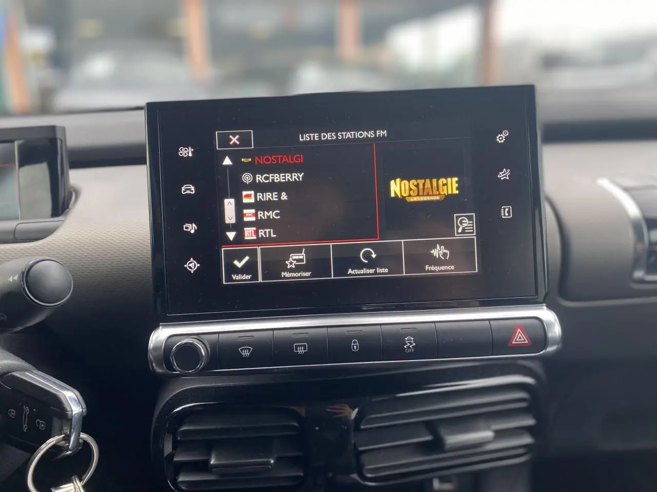 Vue rapprochée de l’écran tactile central du tableau de bord de la Citroën C4 Cactus 2015, affichant la liste des stations FM.