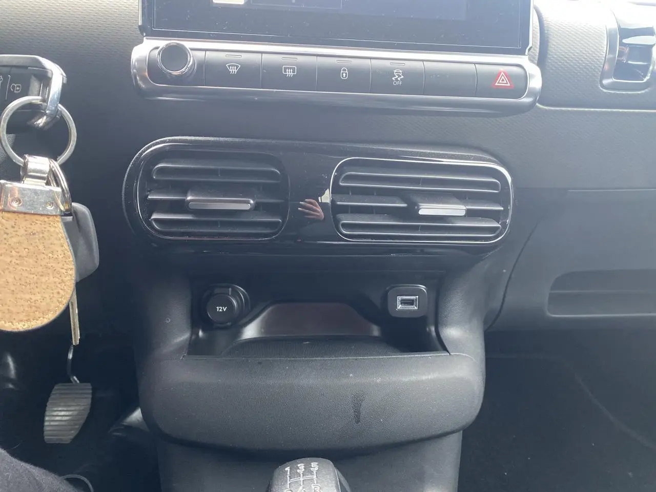 Vue rapprochée de la console centrale noire avec aérateurs, prise 12V, port USB et levier de vitesses manuel d'une Citroën C4 Cactus.