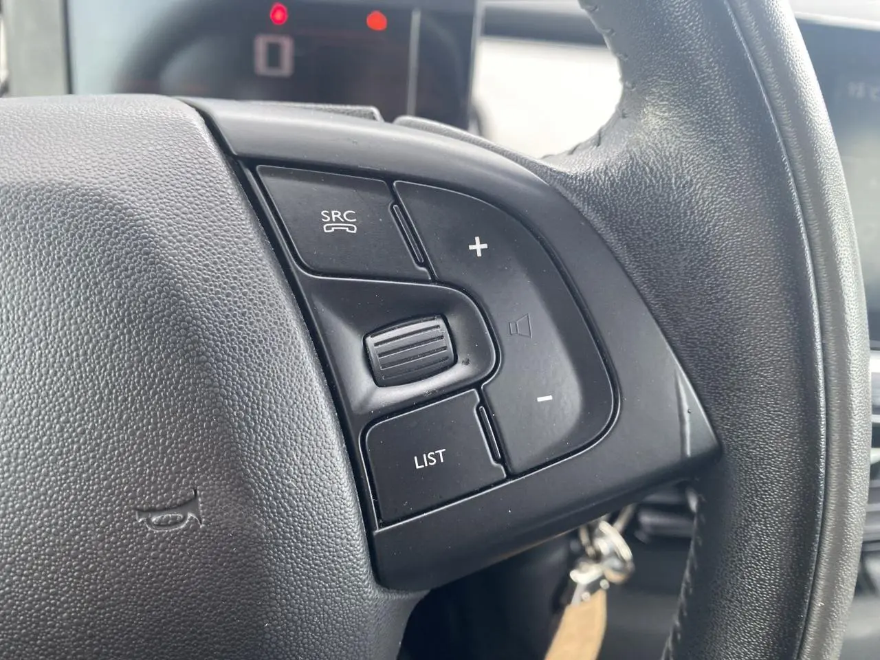 Gros plan sur les commandes au volant noir de la Citroën C4 Cactus blanche, côté droit du volant.