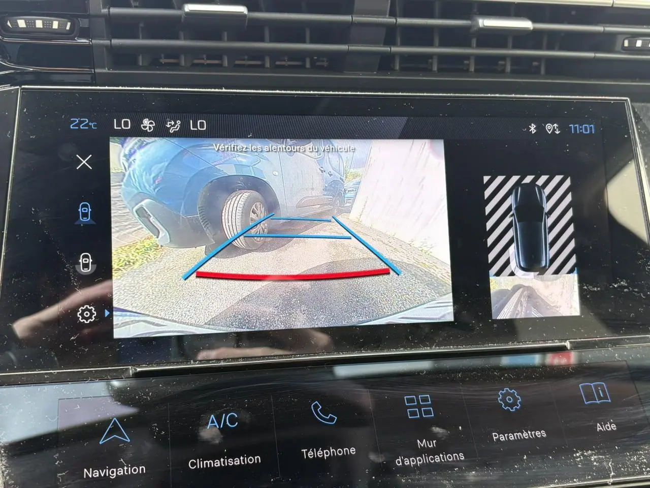Écran tactile intérieur montrant la caméra de recul avec vue sur roue arrière gauche d’une Peugeot 308 Bleu Obsession.