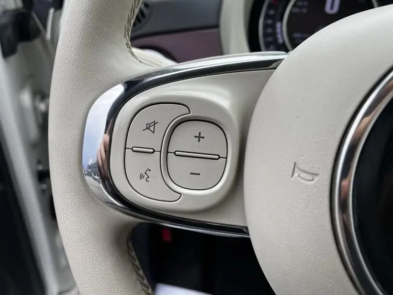 Gros plan sur les commandes blanches du volant côté gauche de la Fiat 500C blanche 2020, version Diva Dualogic.