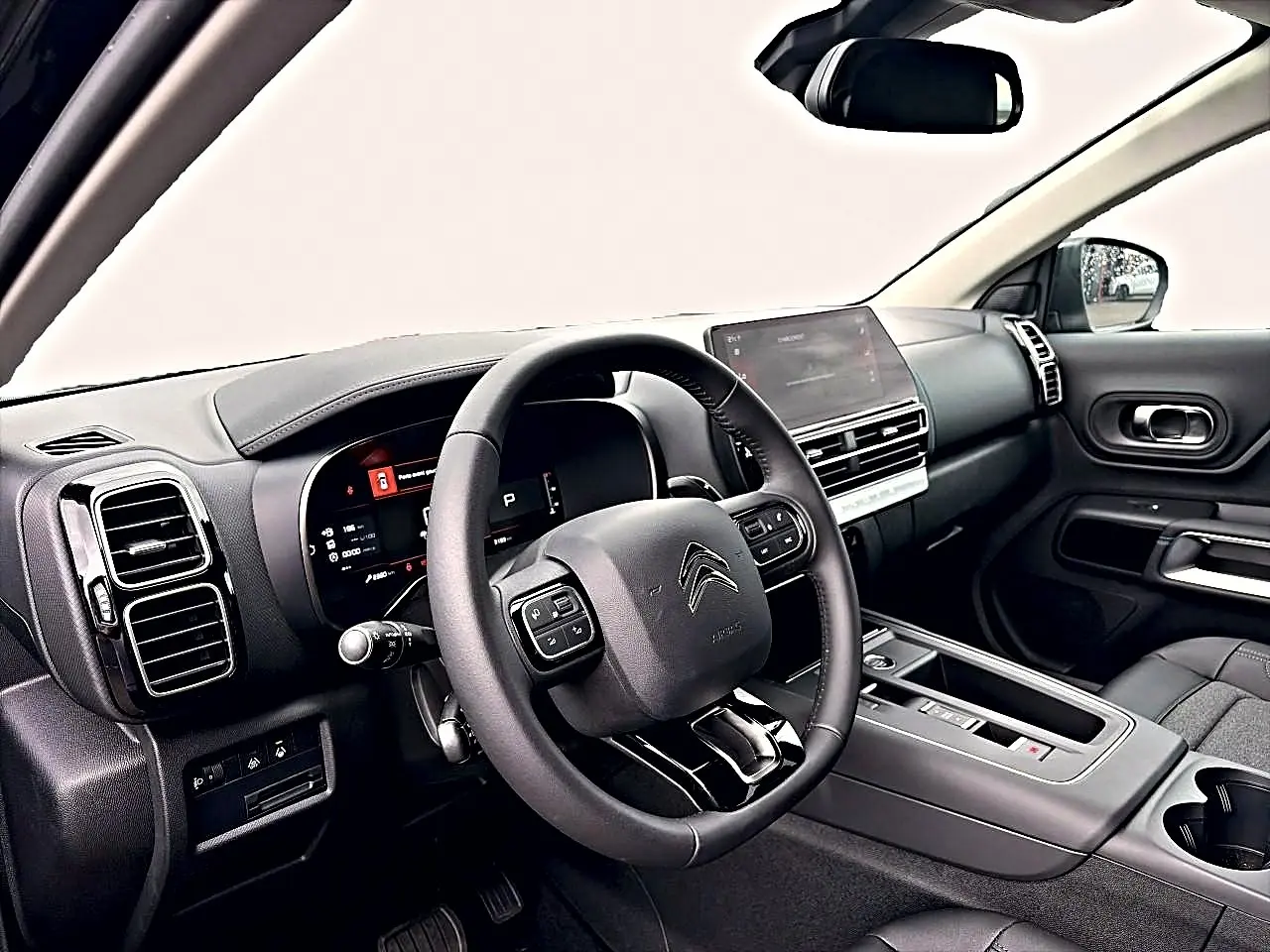 Intérieur noir du Citroën C5 Aircross 2025 vu côté conducteur, volant cuir multifonction et écran tactile central.