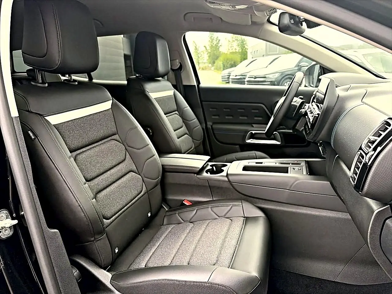 Vue intérieure côté droit du Citroën C5 Aircross 2025 noir, sièges avant en cuir et tissu avec accoudoir central.