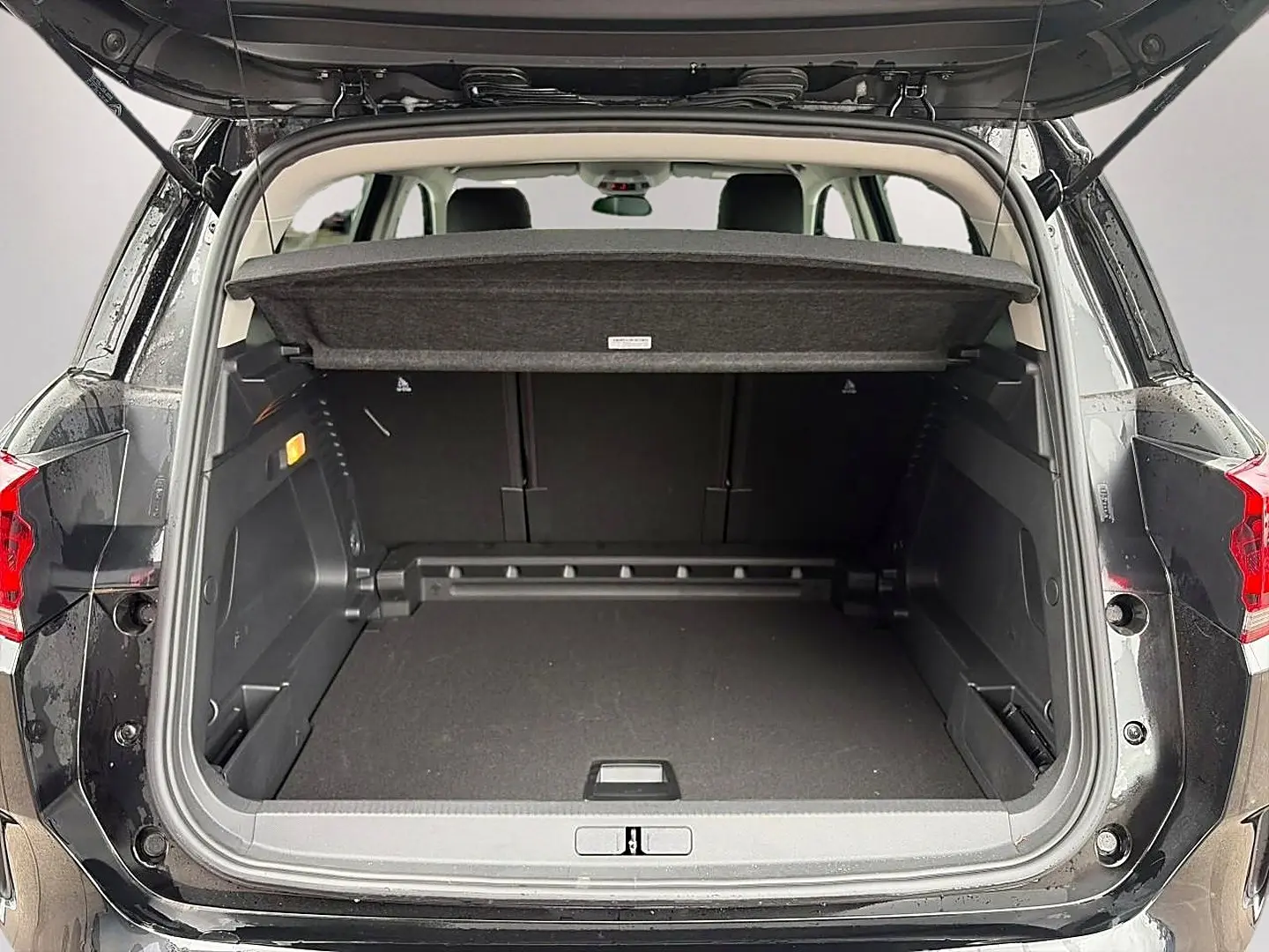 Coffre ouvert vu de l'arrière d'un Citroën C5 Aircross noir 2025 avec cache-bagages et banquette arrière visible.